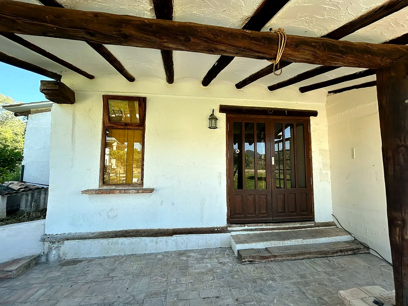 Veranda mit Holzbalken und frisch gestrichenen weißen Wänden