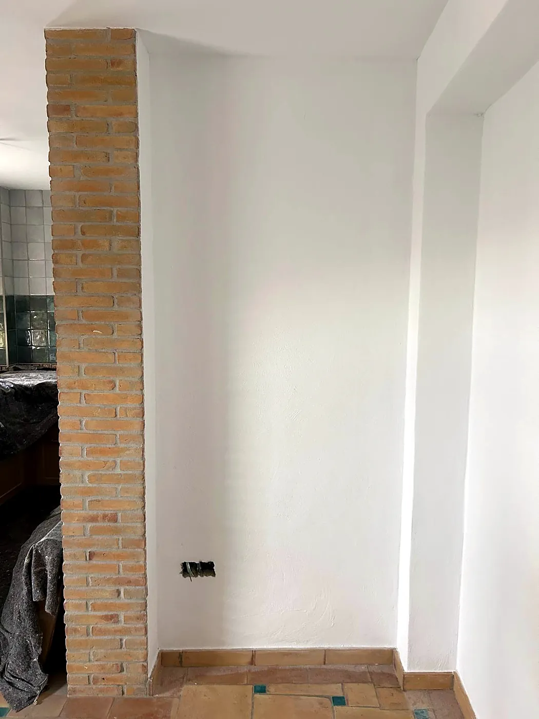 Weiße Wand neben einem Pfeiler aus Sichtmauerwerk